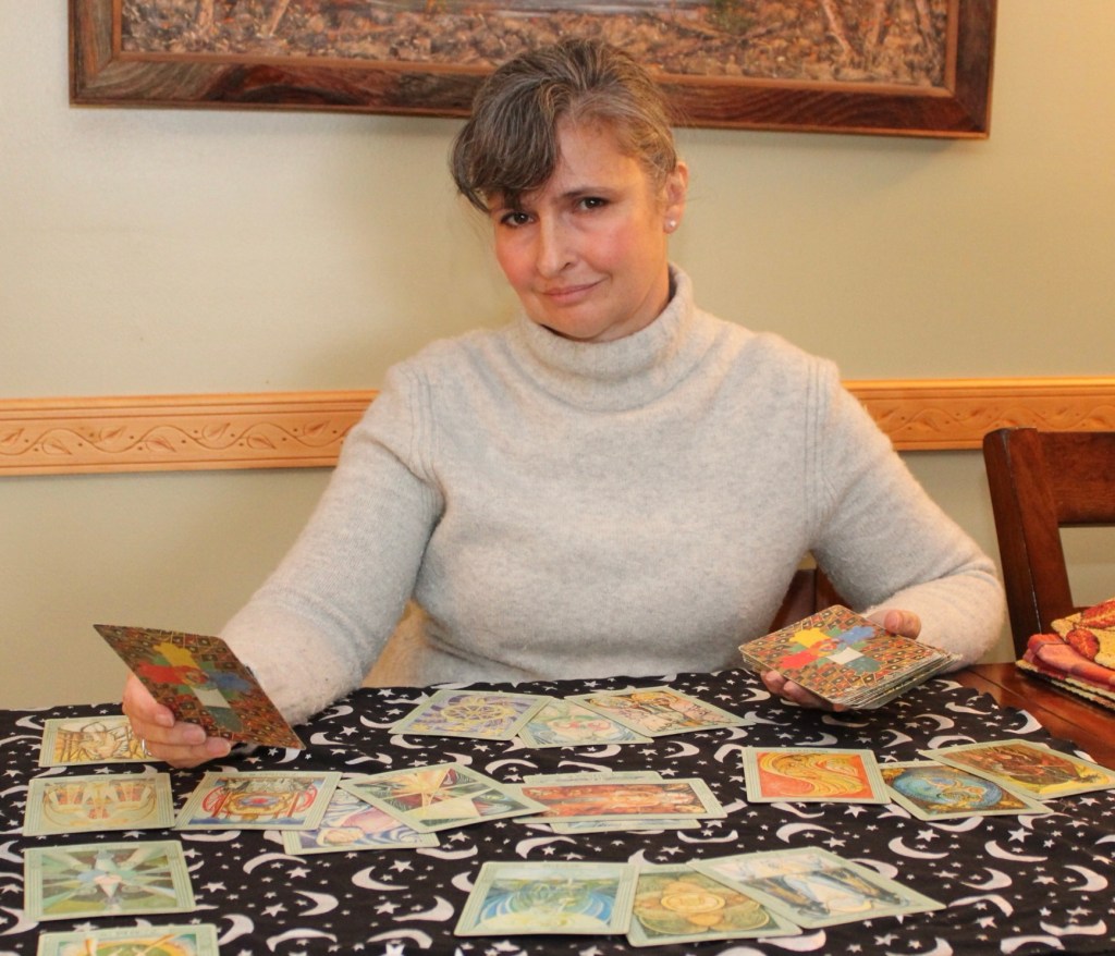 Alison sitting at a table reading a tarot layout.